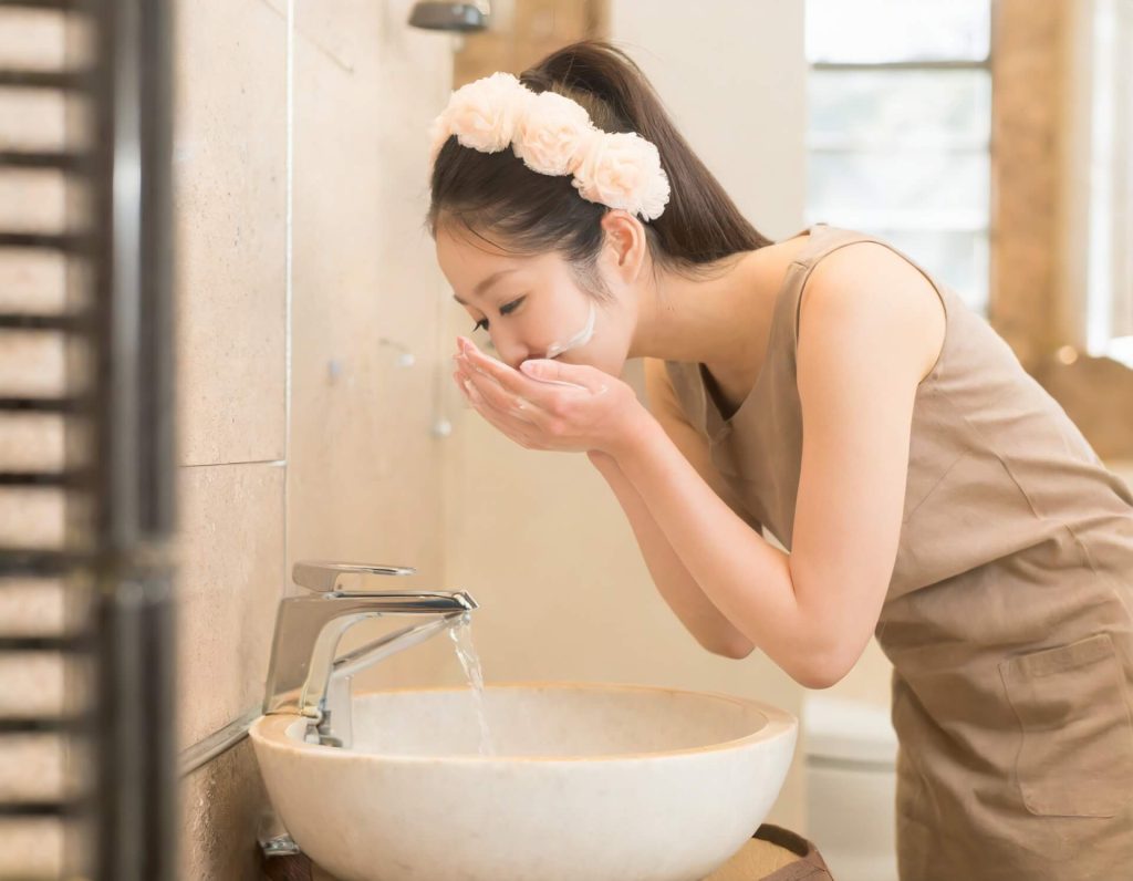 女人在浴室水槽裡洗臉