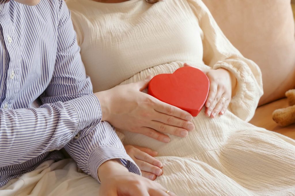 一個男人和一個女人在懷孕的肚子前抱著一顆心